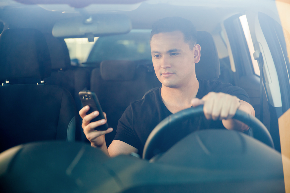man using his smartphone behind the wheel